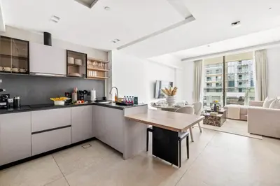 a kitchen with white cabinets and a table in a room at Large 2BR with Work Desk, Pool, Gym and Kids Area in Dubai