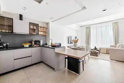 a kitchen with white cabinets and a wooden table at Large 2BR with Work Desk, Pool, Gym and Kids Area in Dubai