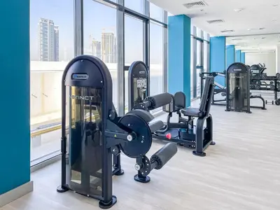 a gym with several tread machines in a room with windows at Bright and Sleek Azizi Studio Prime Meydan Location in Dubai