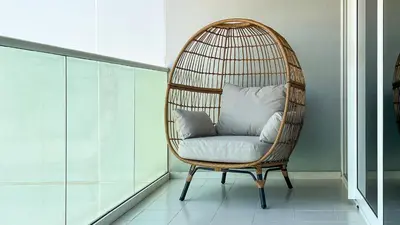 a rattan chair with a pillow in a room at KeyRock Living - Chic Reva 1BR with Pool Access in Dubai