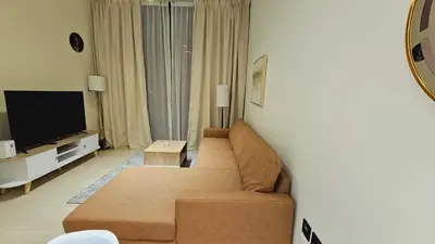 a living room with a couch and a flat screen tv at Spacious 1BR Apartment in Binghatti Emerald JVC in Dubai