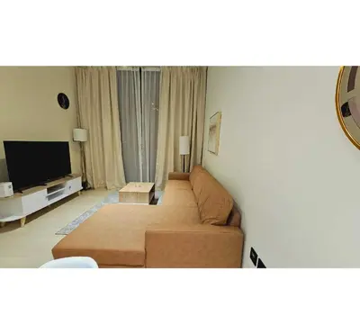 a living room with a couch and a flat screen tv at Spacious 1BR Apartment in Binghatti Emerald JVC in Dubai