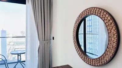 a round mirror hanging on a wall next to a window at Premium 1 Bed Apartment In Binghatti Venus in Dubai