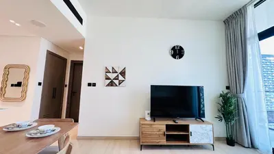 a living room with a tv and a table at Premium 1 Bed Apartment In Binghatti Venus in Dubai