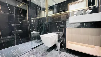 a black tiled bathroom with a toilet and a sink at OYO HOME 1457 Premium 1bed Apartment In Jvc Bh in Dubai
