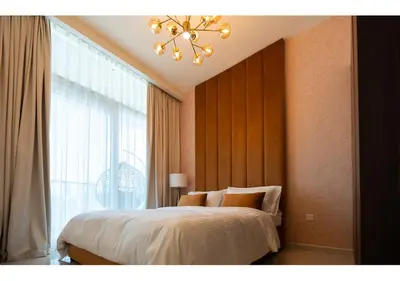 a bedroom with a bed with a chandelier and a window at Reva Residence - Luxe 1BR with Burj Khalifa View in Dubai