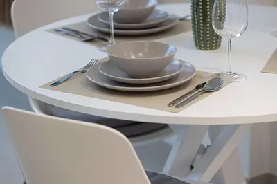 a white table with plates and bowls and silverware at Cozy 1 BR with gym & pool just 15min to Dubai Marina in Dubai