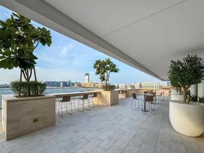 a patio with tables and chairs and a view of the water at Coastal Elegance 1-Bedroom in Grand Bleu in Dubai