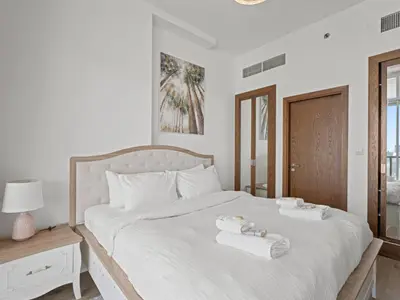 a white bedroom with two towels on a bed at Spacious and Cozy 1BDR in Hameni in Dubai