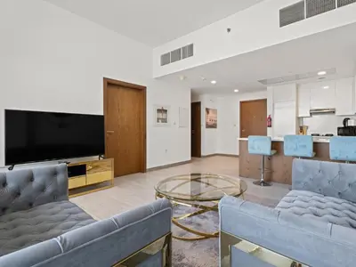 a living room with couches and a flat screen tv at Spacious and Cozy 1BDR in Hameni in Dubai