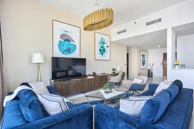 a living room with a blue couch and a tv at Frank Porter - Palm View in Dubai