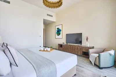 a bedroom with a bed and a tv and a chair at Frank Porter - Palm View in Dubai