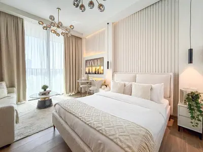 a bedroom with a large bed and a living room at Modern Chic Studio Apartment, Belgravia Heights 2, JVC Dubai in Dubai