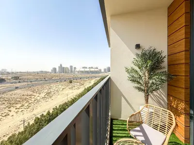a balcony with a chair and a palm tree at Modern Chic Studio Apartment, Belgravia Heights 2, JVC Dubai in Dubai
