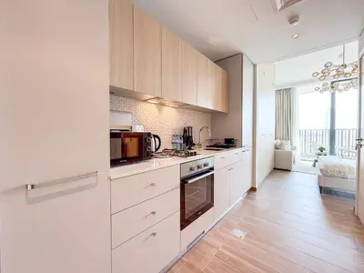 a kitchen with white cabinets and a large window at Modern Chic Studio Apartment, Belgravia Heights 2, JVC Dubai in Dubai
