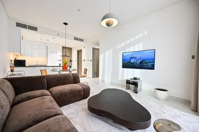 a living room with a brown couch and a table at Stunning 1 Bdr Luxury District one in Dubai