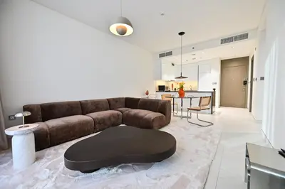 a living room with a brown couch and a table at Stunning 1 Bdr Luxury District one in Dubai