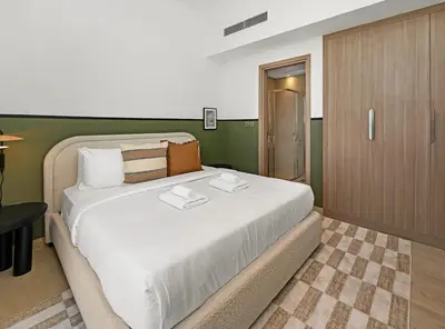 a bedroom with a large white bed with a green wall at Stylish Azizi 1 Bedroom in Dubai