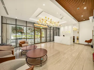 a lobby with tables and chairs in a building at Stylish Azizi 1 Bedroom in Dubai