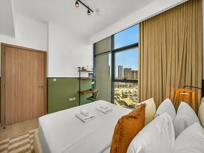 a bedroom with a white bed and a large window at Stylish Azizi 1 Bedroom in Dubai