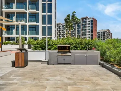 a patio with a grill with buildings in the background at Stylish Azizi 1 Bedroom in Dubai