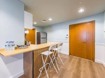 a kitchen with a wooden counter with stools in it at Stylish 1-Bedroom with Panoramic Partial Sea View in Dubai