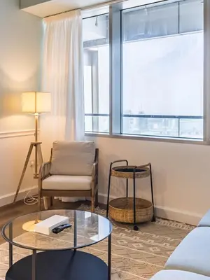 a living room with a glass table and a chair at Stylish 1-Bedroom with Panoramic Partial Sea View in Dubai