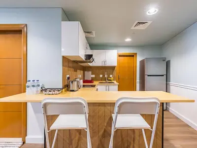 a kitchen with a wooden counter with two stools at Stylish 1-Bedroom with Panoramic Partial Sea View in Dubai