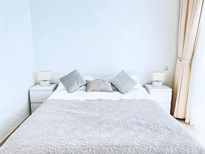 a white bedroom with a large bed with two night stands at Private Beach Access - Canal View in Dubai