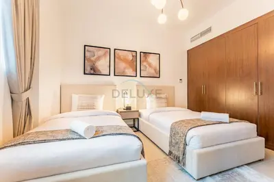 two beds in a bedroom with wooden cabinets at City View 2BR Just Steps from the Mall, Roxana Residence B, Jumeirah Village Circle by Deluxe Holiday Homes in Dubai