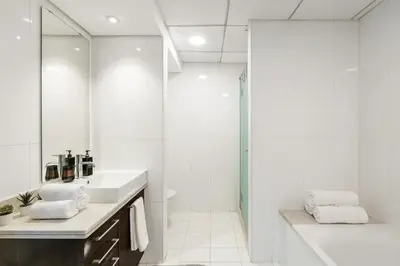 a white bathroom with a sink and a shower at 2BR in Downtown with Burj Khalifa & Fountain views in Dubai