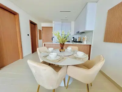 a dining room with a white table and chairs at Stylish 1br In Jvc Balcony, Pool & Free Parking in Dubai