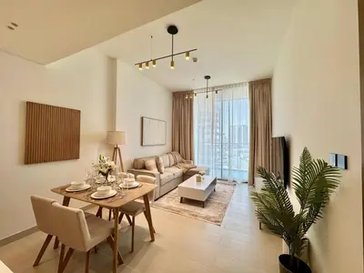a living room with a table and a couch at Jvc 1br Oasis Serene Interiors Pool & Parking in Dubai