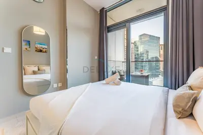 a bedroom with a large white bed and a large window at Dubai Canal and City Views 1BR, Minutes Drive to Burj Khalifa, DAMAC Zada Tower, Business Bay by Deluxe Holiday Homes in Dubai