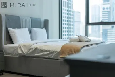 a bed in a room with a large window at Mira Holiday Homes - Newly and modern 1 bedroom with lake view in JLT in Dubai