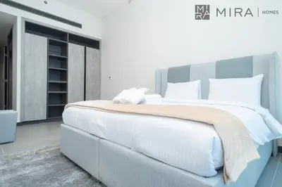 a bedroom with a large bed with white sheets and pillows at Mira Holiday Homes - Newly and modern 1 bedroom with lake view in JLT in Dubai