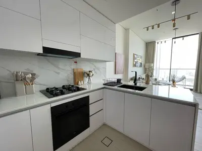 a kitchen with white cabinets and a black stove top oven at Bright 1br Jvc Balcony & Free Parking in Dubai