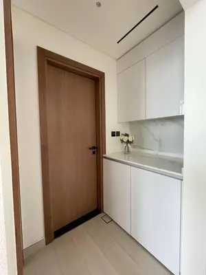 a kitchen with white cabinets and a wooden door at Bright 1br Jvc Balcony & Free Parking in Dubai