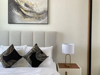 a bed with white pillows and a painting on the wall at Bright 1br Jvc Balcony & Free Parking in Dubai