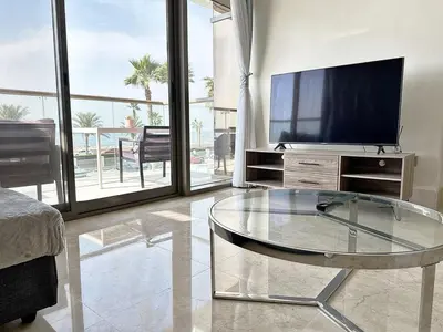 a living room with a tv and a glass table at AURA -Direct Seafront 2BR-Palm in Dubai