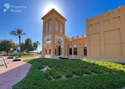 a building with a clock tower in a park at Cozy Studio Apartment in Meydan in Dubai