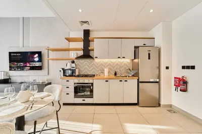 a kitchen with a refrigerator and a table with chairs at Cozy 1BR in Socio Dubai Hills Near Mall and Park in Dubai