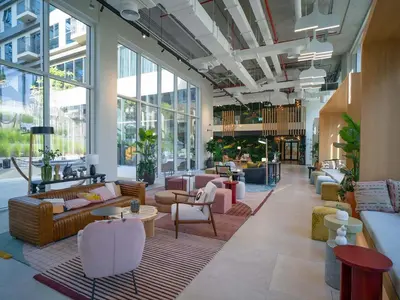 a large lobby with couches and tables and windows at Cozy 1BR in Socio Dubai Hills Near Mall and Park in Dubai