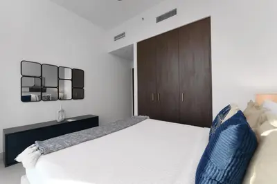 a bedroom with a white bed and a wooden cabinet at Elite Escape - 3 BHK Burj View & Dubai Mall Access in Dubai