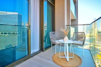 a balcony with two chairs and a table with a vase on it at High Floor Burj and Canal View Business Bay in Dubai