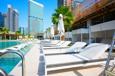a row of chaise lounge chairs next to a pool at High Floor Burj and Canal View Business Bay in Dubai