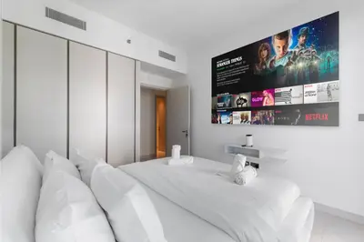 a bedroom with a white bed with a large screen at Full Sea View & Dubai Skyline - 4BR LUX Beachfront in Dubai