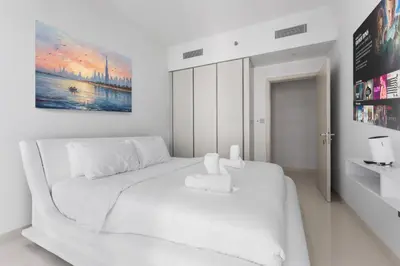 a white bedroom with a white bed and a painting at Full Sea View & Dubai Skyline - 4BR LUX Beachfront in Dubai