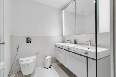 a white bathroom with a toilet and a sink at Full Sea View & Dubai Skyline - 4BR LUX Beachfront in Dubai