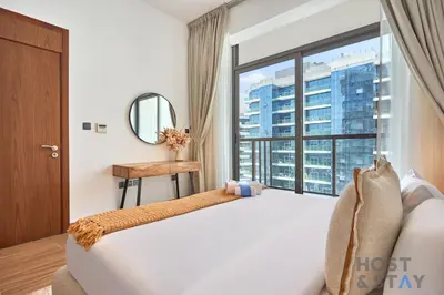 a bedroom with a white bed and a large window at Boho-Chic Comfort - 1BR Haven - Marquis 2020 Arjan in Dubai